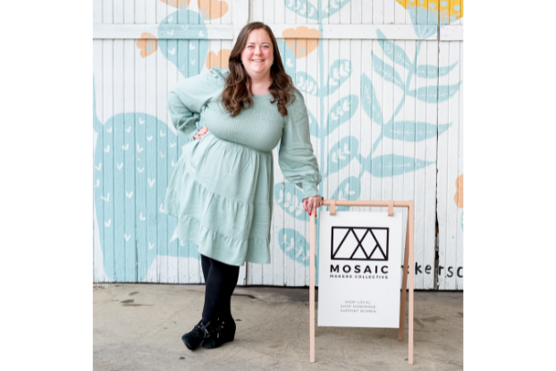 Katy Sensenig Schilthuis, Founder of Mosaic Makers, posing with her business sign.