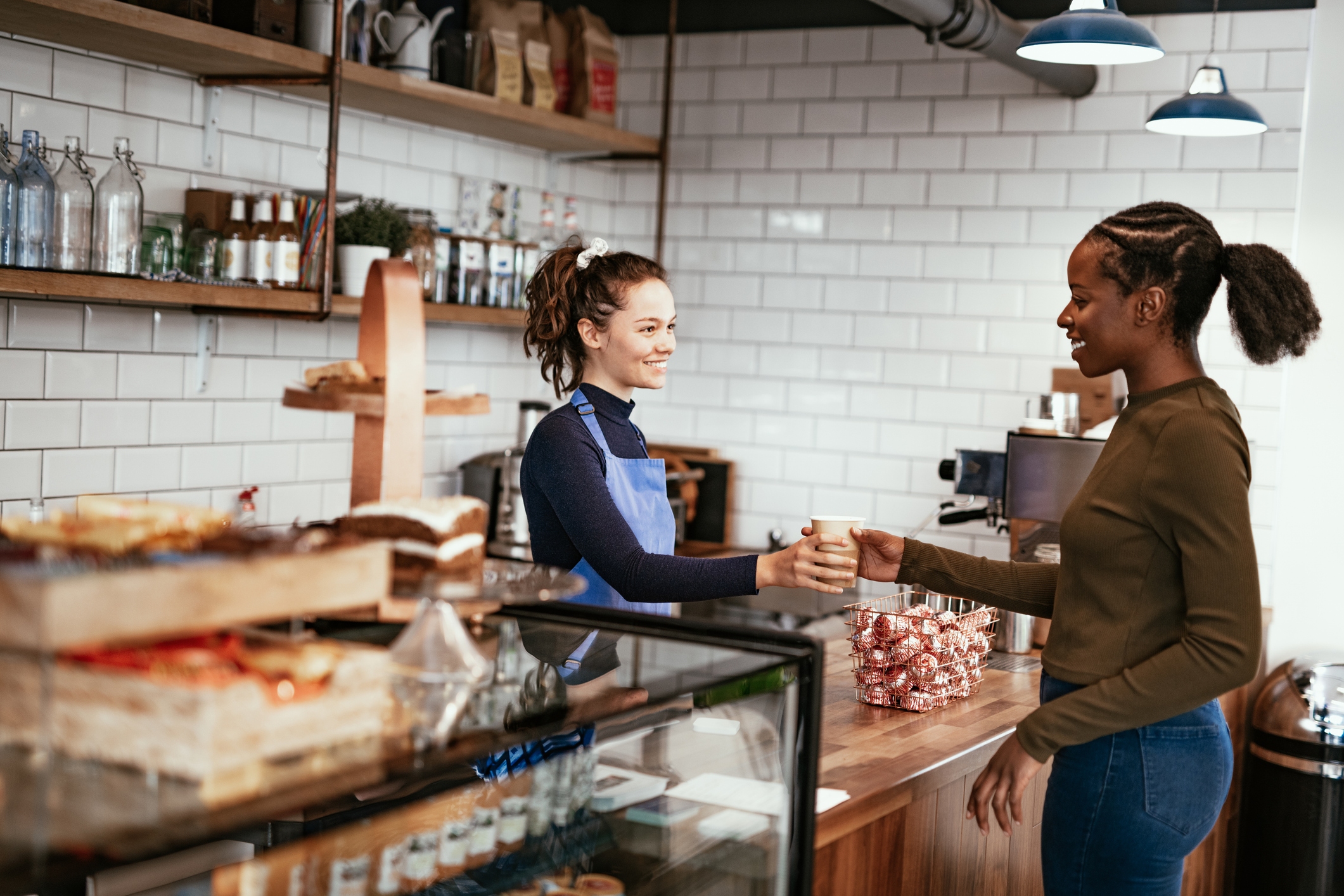 A cafe employee handing a cup to a customer inside a cafe.