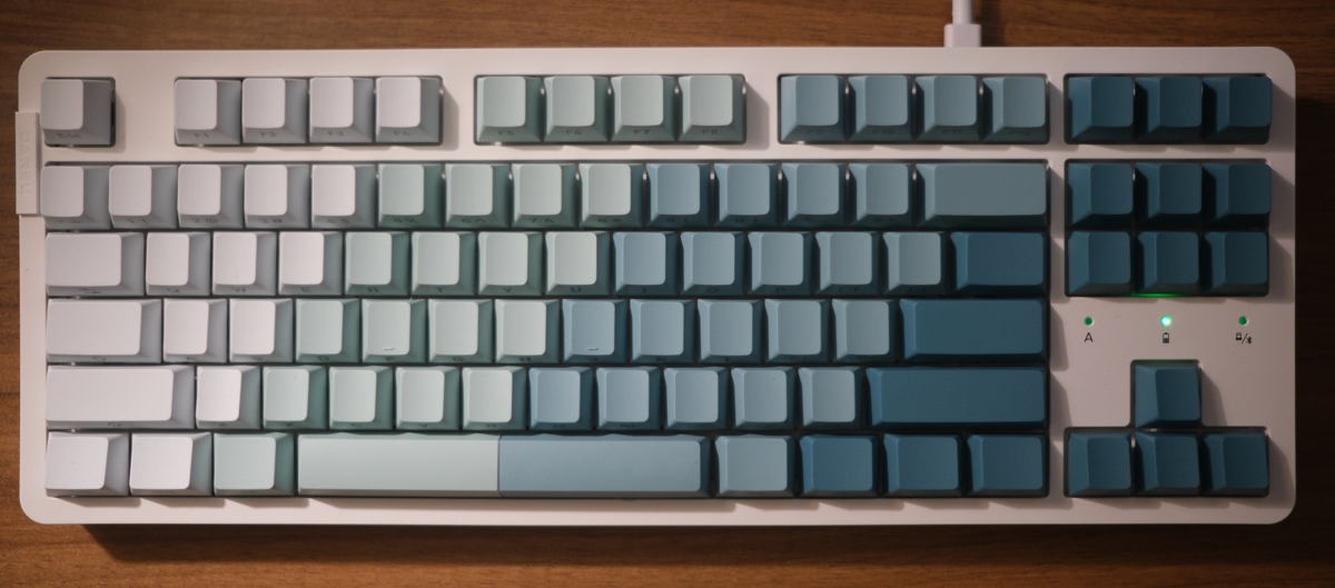 An overhead view of the Dareu EK87 Pro Keyboard, which has blank keycaps with a horizontal, white to green gradient.