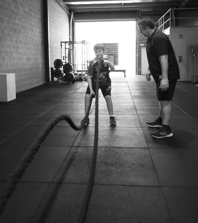 Youth Strength and Athletic Development Dubbo Man coaching younger man in a gym. Young man holding battle ropes