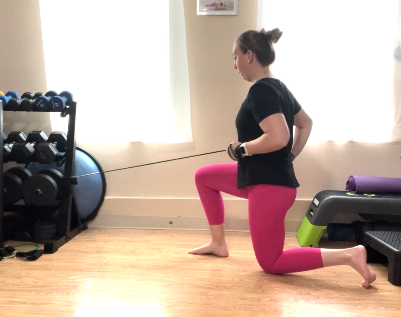 A female in a half kneeling position doing a row with a band