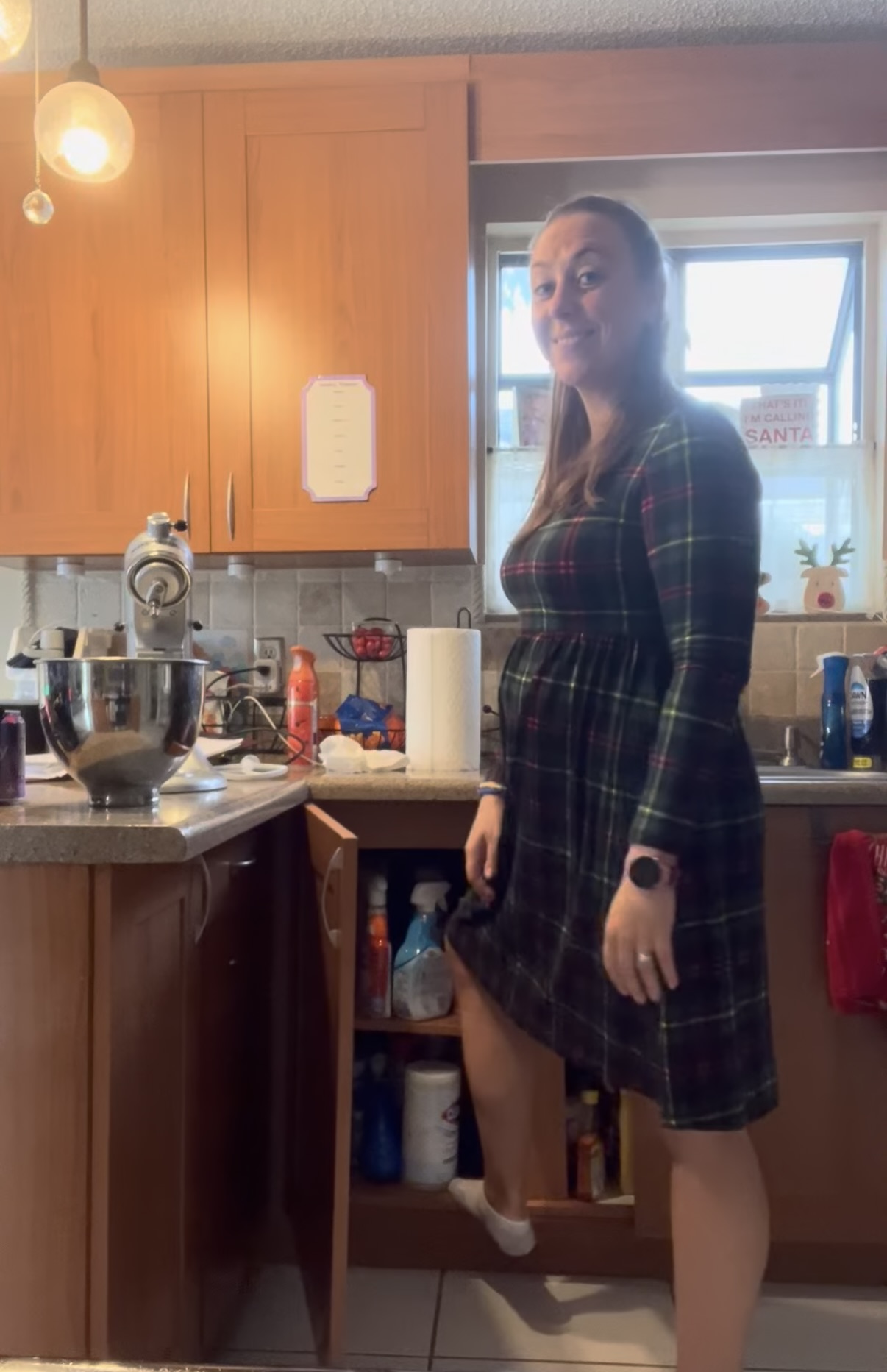 Mom Standing with her foot on the bottom shelf of a kitchen cabinet