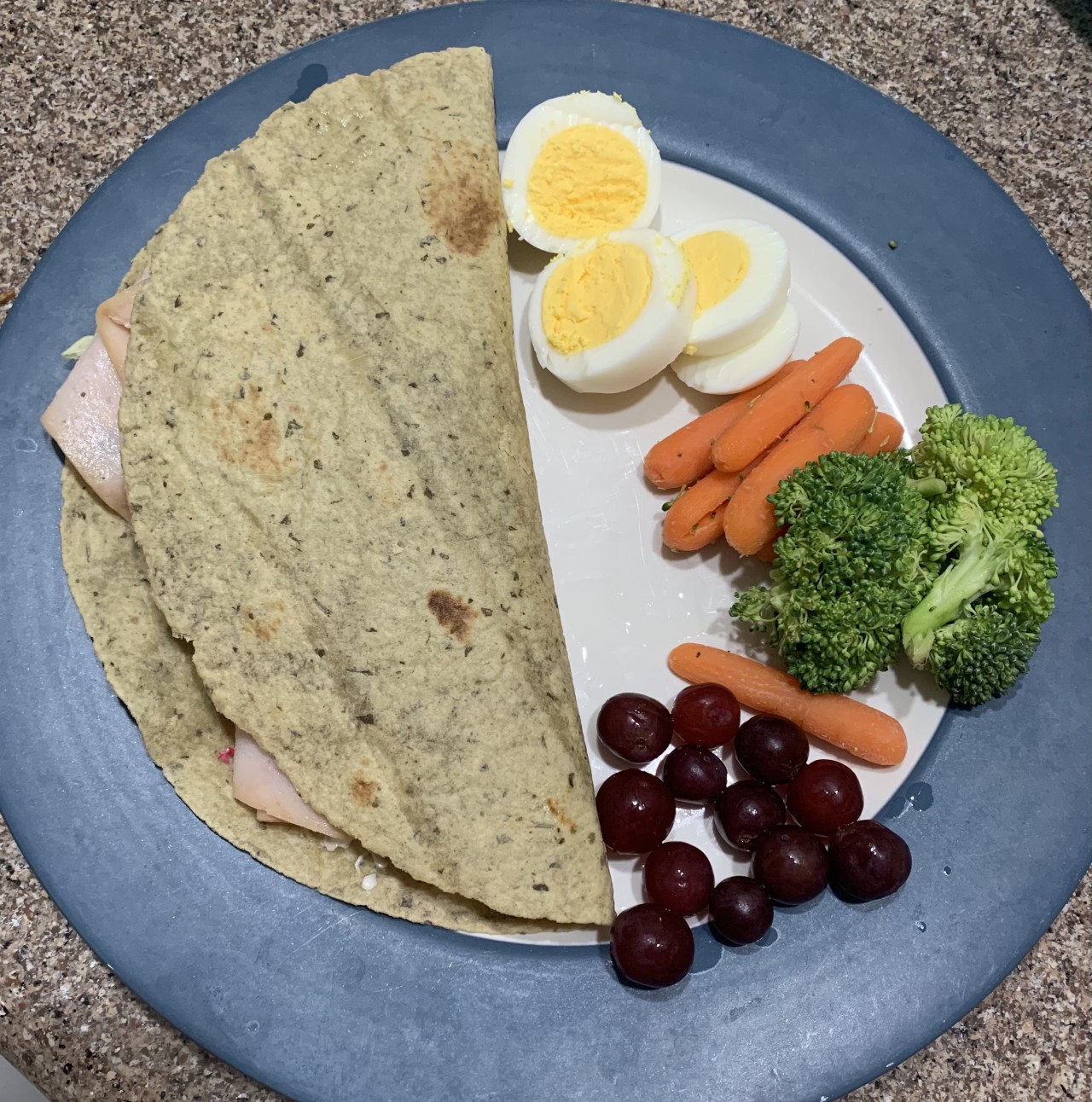 A wrap, boiled eggs, carrots, broccoli, and grapes