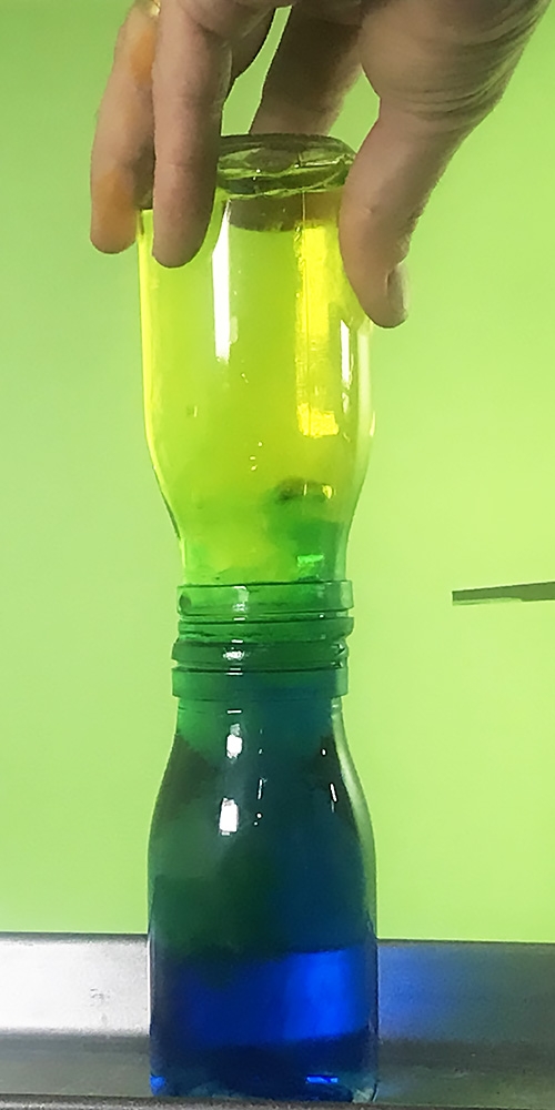 Two bottles on joined together with colourufl water moving betwen them