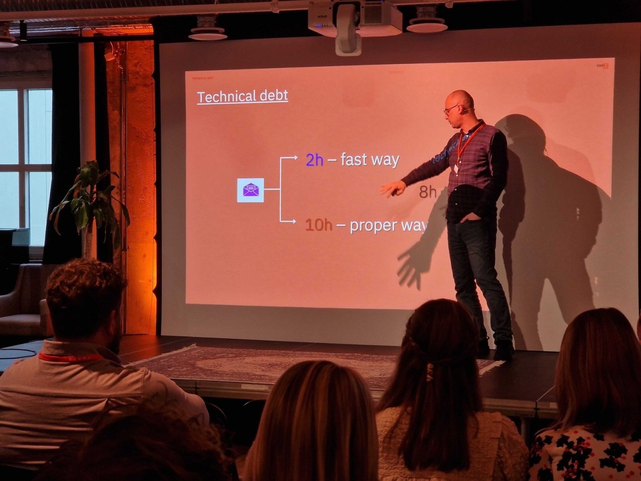 Dalibor on stage pointing at a slide about technical debt