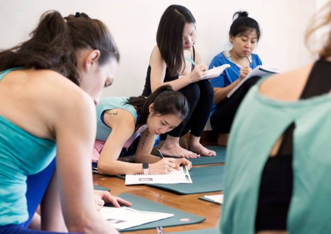 Students learning with training manuals during Power to Lead 200-hour yoga teacher training in Lisbon, Portugal