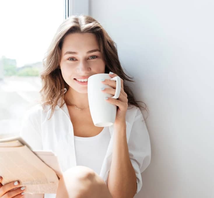 Kvinna sitter med en kopp kaffe och ler – symbol för individuell coaching med Carita Juselius som hjälper dig att skapa verklig förändring i livet