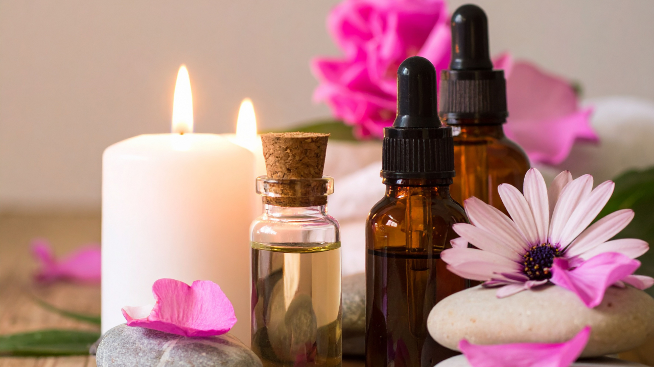 Composición de bienestar con velas encendidas, frascos de aceites esenciales y Flores de Bach, flores y piedras, evocando un ambiente de calma y terapia holística