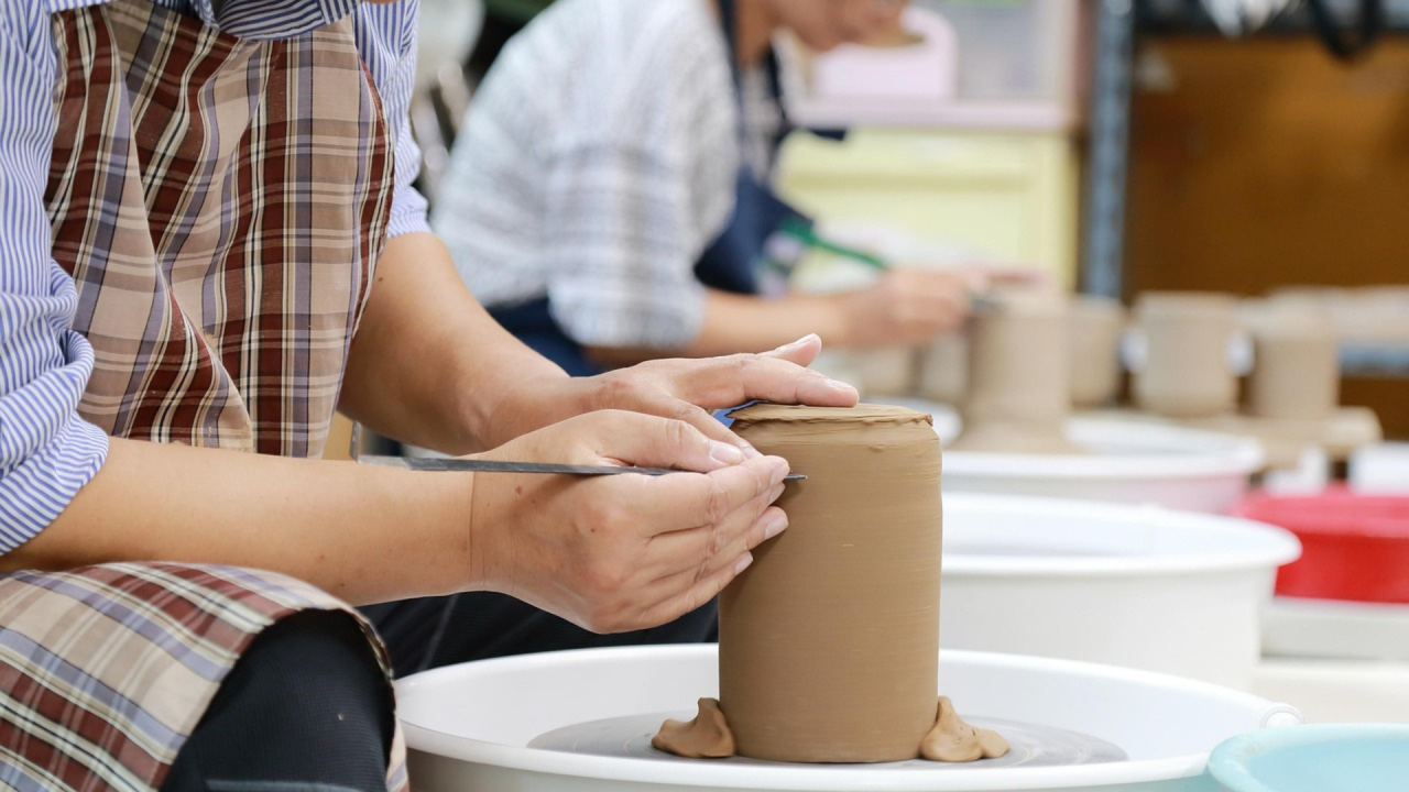 person learning to make a pot sitting at a pottery wheel