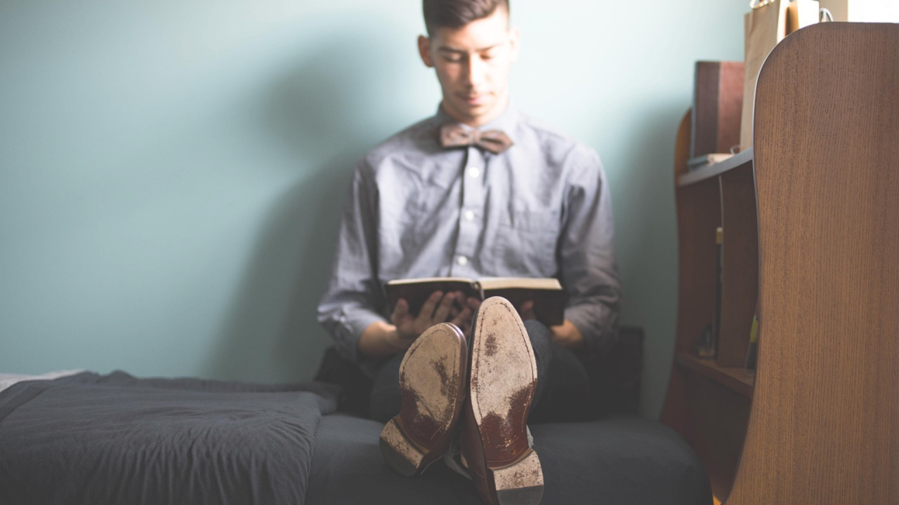 Man sitting on a bed reading a book