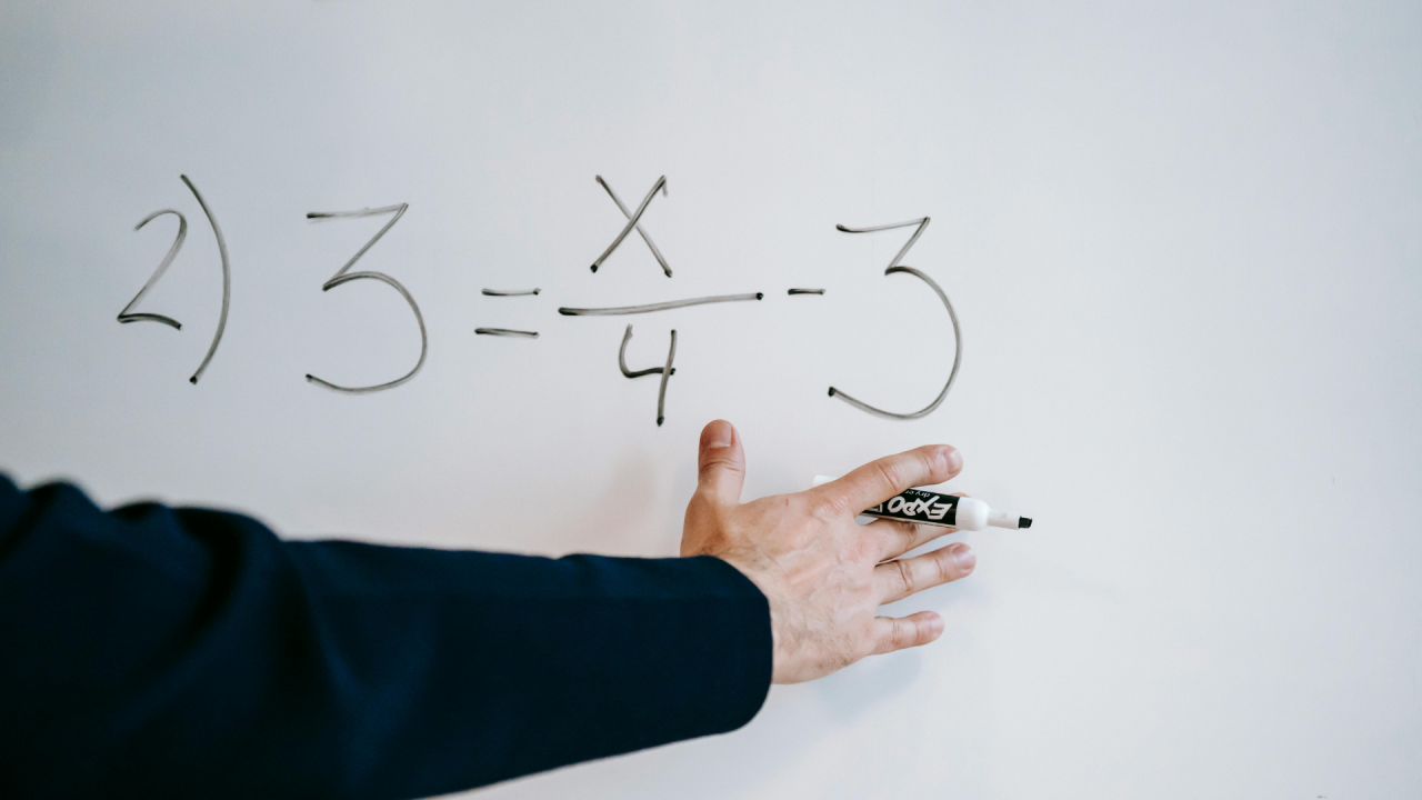 someone writing a maths calculation on a white board