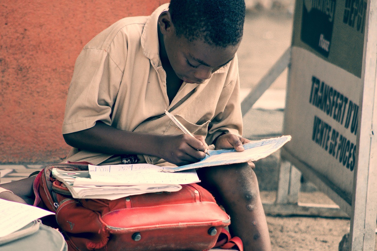 Black boy writing in a book