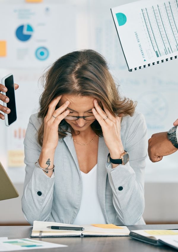 stressed-out woman at desk, resting her head in her hands