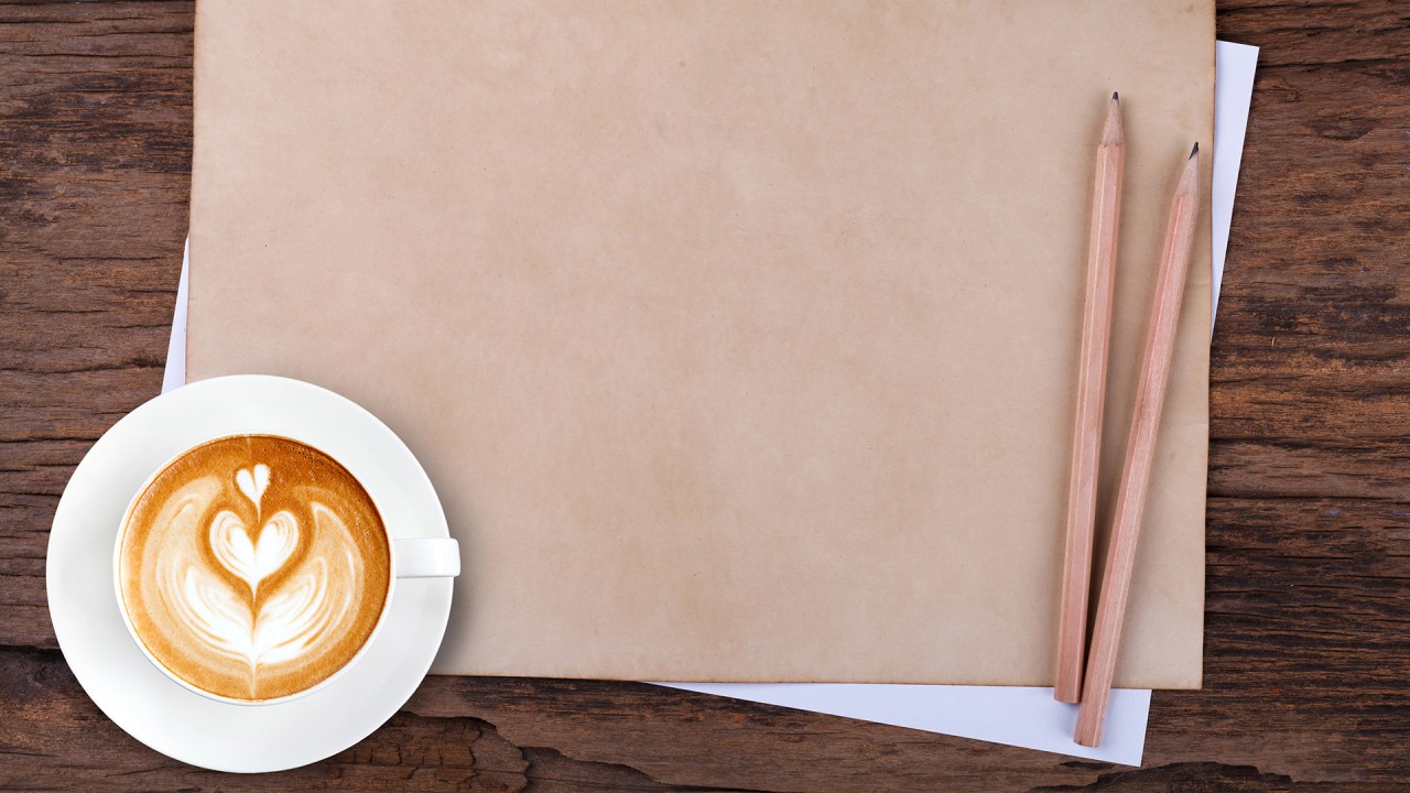 Bild med penna, anteckningsbok och en cappucino, symbol för reflektion och handling