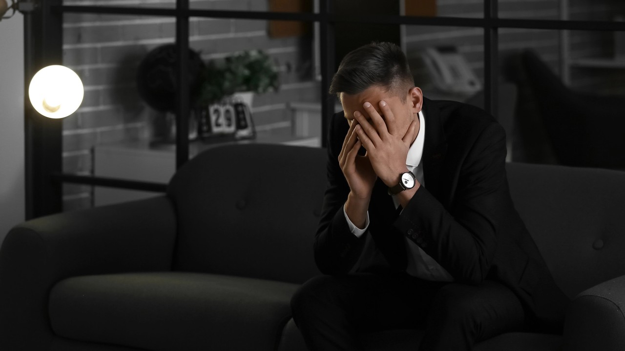 Stressad chef i svart kostym som tappat riktning – symbol för inre press, brist på mening och behovet av reflektion i chefsrollen.