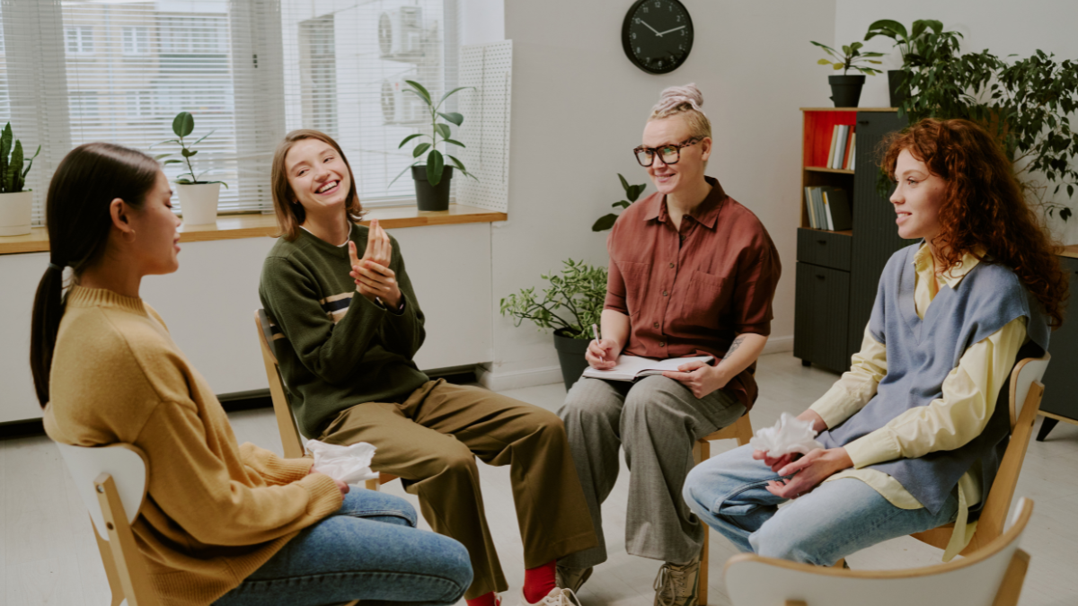 Group of women seated in circle discussing personal topics in a cozy room