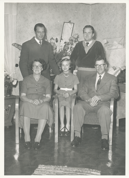 Svartvitt familjefotografi med fem personer ur familjen Hedblom i ett rum.