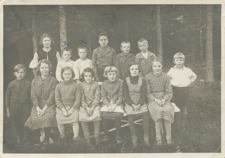 Svartvitt klassfotografi med skolbarn och lärare utomhus, där Erling och Eskil finns med.