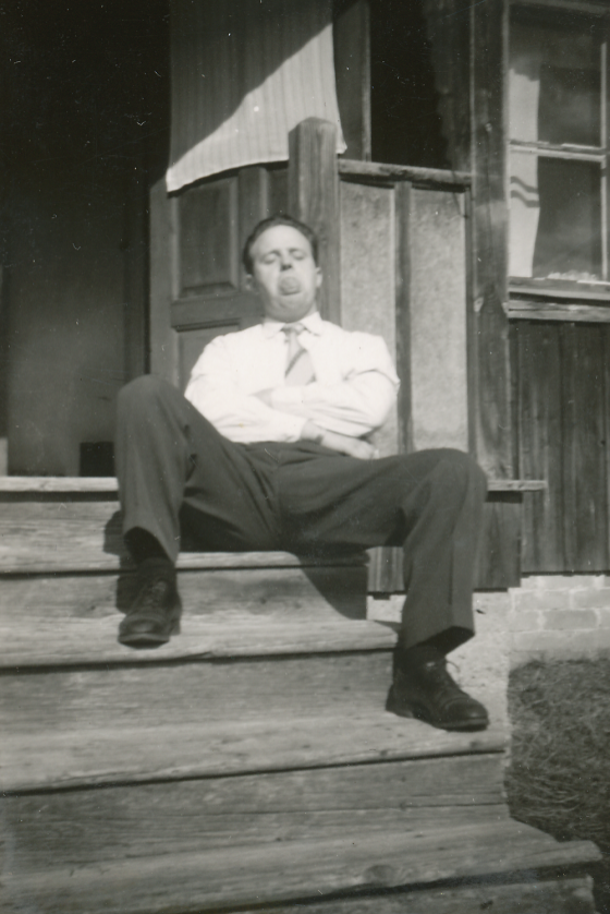 Svartvitt fotografi av Erling sittande på en trappa utanför ett hus.