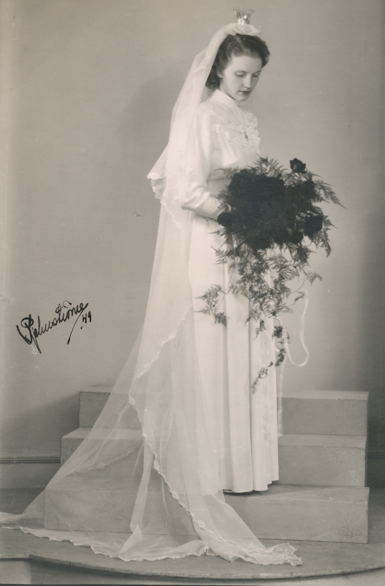 Svartvitt bröllopsfotografi av Mary ensam i brudklänning med lång slöja och bukett.