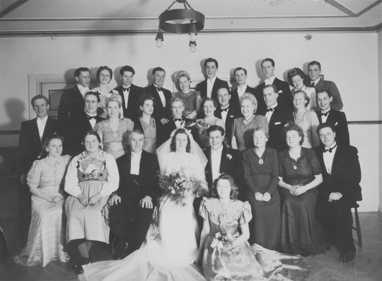 Svartvitt gruppfotografi från Rut och Folkes bröllop med många släktingar och vänner samlade.
