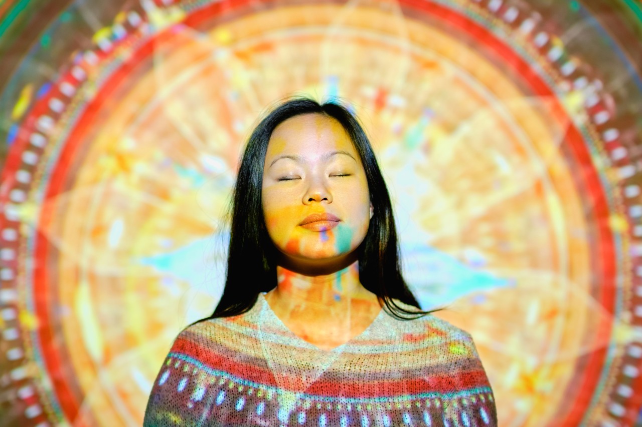 Peaceful woman doing yoga near glowing mandala