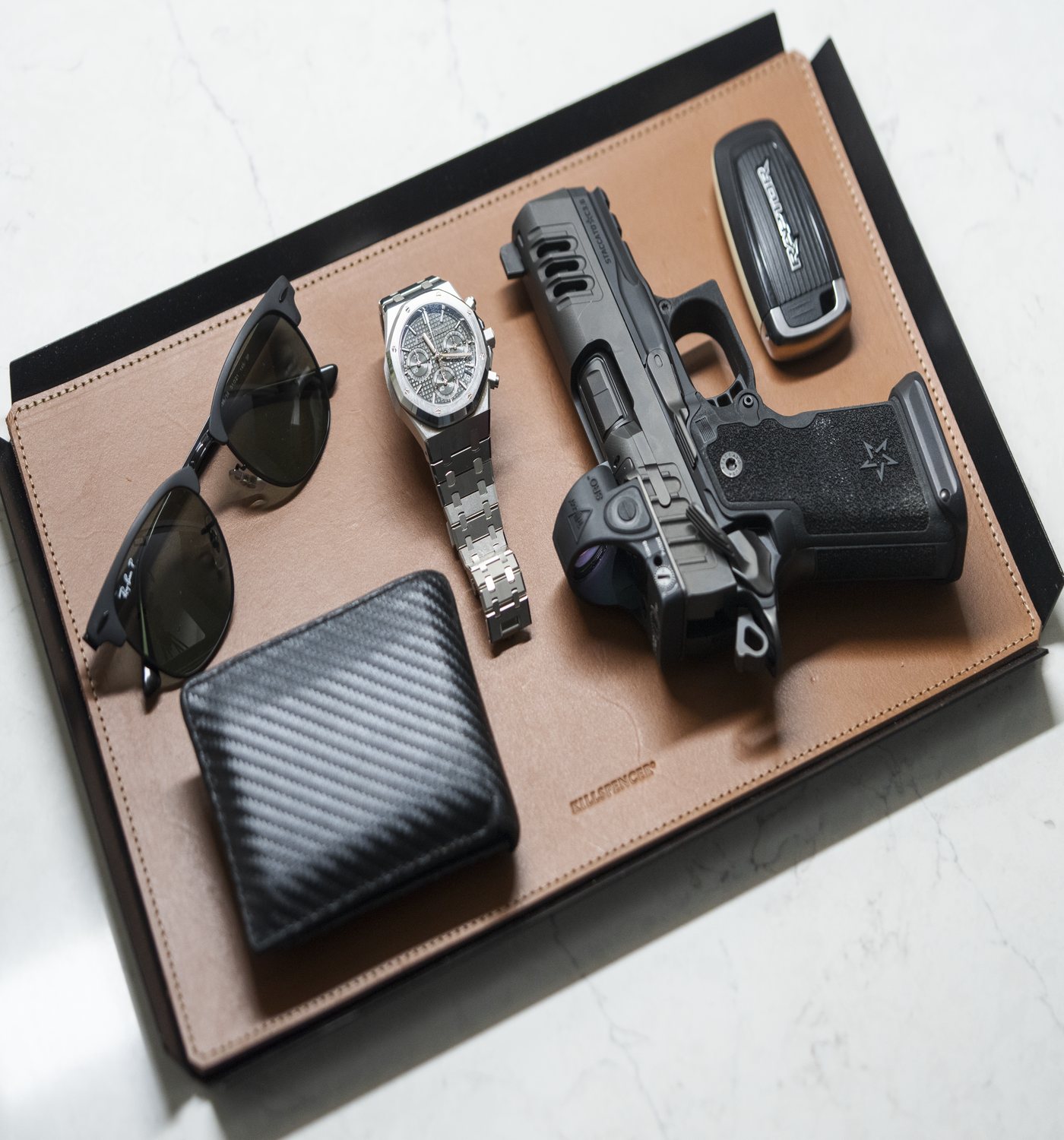 Staccato pistol laid out with a watch, sunglasses, a wallet and a key fob on a leather tray