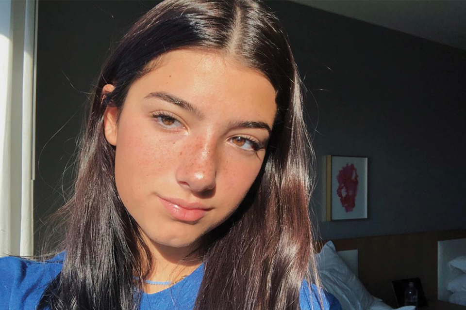 TikTok's Charlie D'Amelio with a blue sweater standing by a window