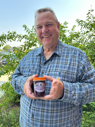 Image of Jon Tester smiling and holding a jar of jam