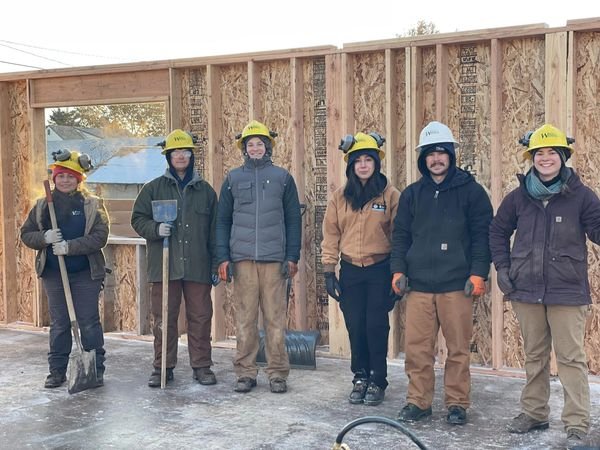 group of people wearing hard hats while standing in front of plywood walls