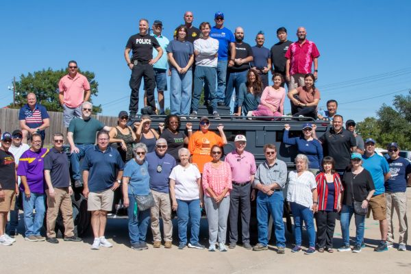 Previous class participants posing around police vehicle