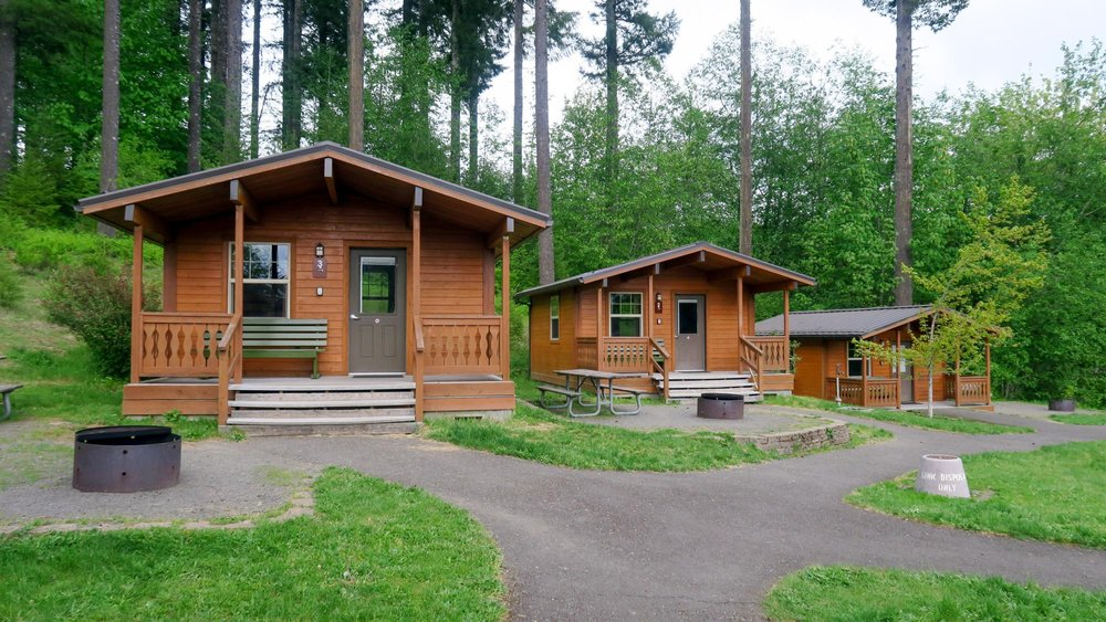 Three cabins in grassy forested area