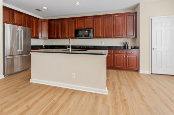 Kitchen with high end fridge, an island with sink, sink, and light wood-type flooring