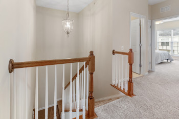 Staircase with light carpet and an inviting chandelier
