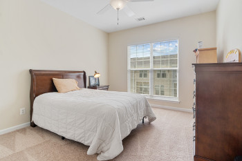 Bedroom with ceiling fan, light carpet, and multiple windows