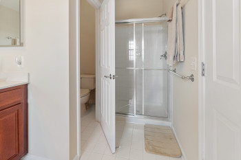 Bathroom featuring tile flooring, walk in shower, vanity, and toilet