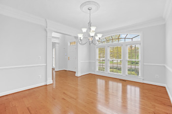 Spare room with plenty of natural light, crown molding, a notable chandelier, and light wood-type flooring