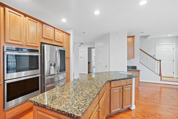 Kitchen with light hardwood / wood-style flooring, stainless steel appliances, a center island, and dark stone counters