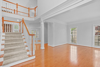 Staircase featuring ornamental molding, light hardwood / wood-style floors, decorative columns, and a towering ceiling