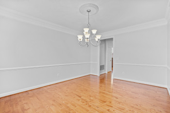 Empty room featuring ornamental molding, a notable chandelier, and light wood-type flooring