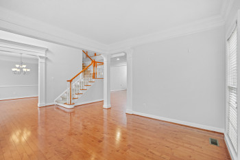 Unfurnished room with light hardwood / wood-style flooring, crown molding, a chandelier, and decorative columns