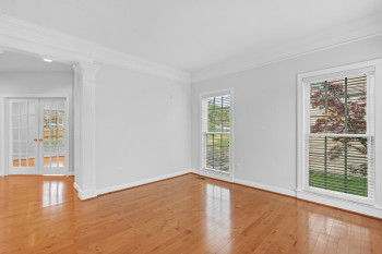 Empty room with french doors, ornamental molding, ornate columns, and light wood-type flooring
