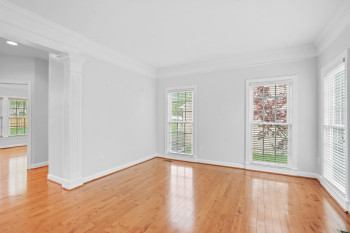 Spare room featuring crown molding, decorative columns, and light wood-type flooring