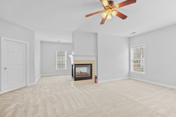Unfurnished living room with ceiling fan, light carpet, and a multi sided fireplace