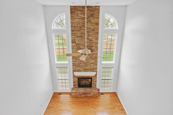 Unfurnished living room featuring light hardwood / wood-style flooring, a wealth of natural light, ceiling fan, and a high ceiling