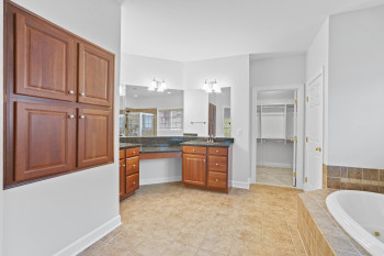 Bathroom featuring tiled tub, vanity, and tile floors