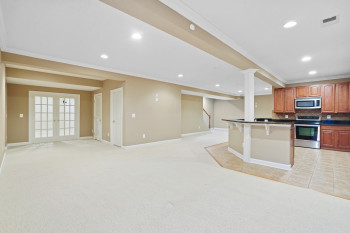 Kitchen with a breakfast bar, ornamental molding, appliances with stainless steel finishes, tasteful backsplash, and light colored carpet