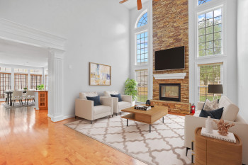 Living room featuring a healthy amount of sunlight, light hardwood / wood-style flooring, and a towering ceiling