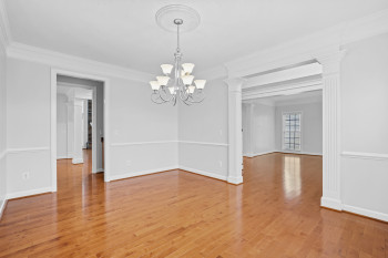 Spare room featuring a chandelier, ornamental molding, decorative columns, and hardwood / wood-style flooring