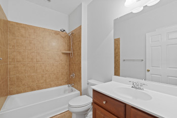 Full bathroom with tiled shower / bath combo, vanity, and toilet
